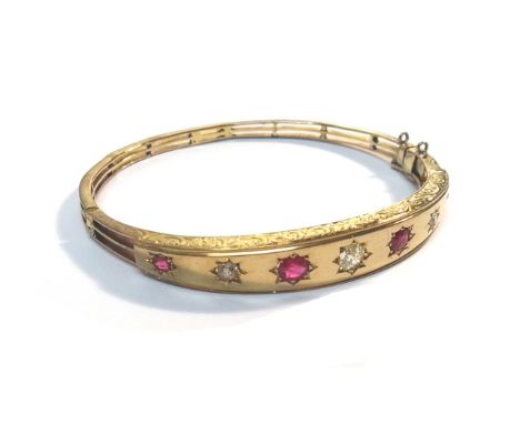 A gold, ruby and diamond set oval hinged bangle, star set with three cushion shaped diamonds, alternating with four cushion s