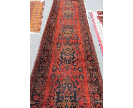 An Afghan runner, the madder field with five single stylised black medallions, a black flower border, 382 x 84cm. 