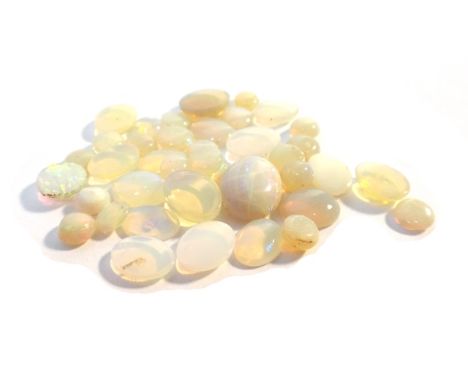 A quantity of unmounted opals, pale blue gems, part of a carved jade panel and two colourless gems.