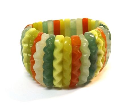 A vary coloured jade bracelet, in an expanding baton shaped panel elasticated design, with spiral decoration to the panels.