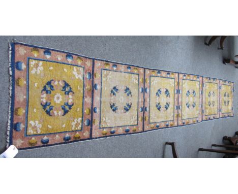 A Ningxia runner late 19th century, with six saffron squared panels, each with floral roundel, 356 x 62cm. 