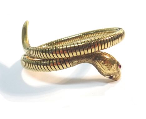 A 9ct gold and cabochon ruby set sprung bangle, designed as a coiled snake, the head mounted with cabochon ruby eyes and othe