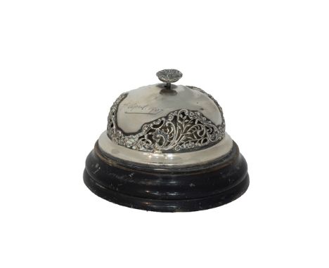 A silver mounted circular wind-up table bell, with pierced decoration, engraved 7th April 1907, a push down button at the top