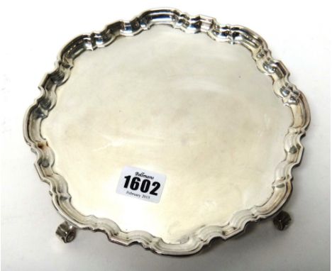 A silver shaped circular salver, decorated with a pie-crust rim in the Chippendale style and raised on four scrolling feet, S
