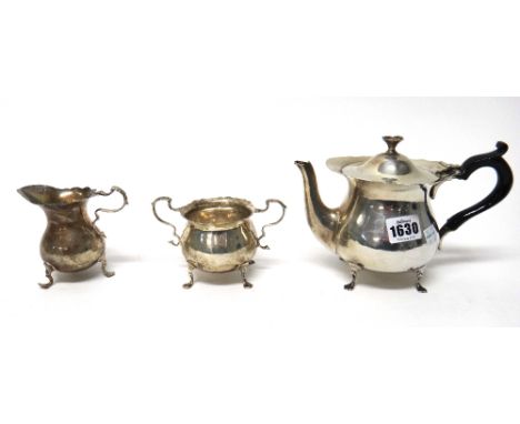 A silver three piece tea set, comprising; a teapot, with a black handle, a twin handled sugar bowl and a milk jug, each piece