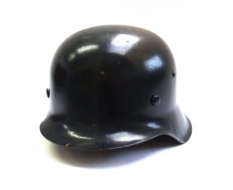 A German World War II helmet, black painted with leather interior and chin strap.