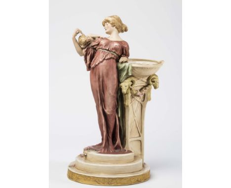 AN ART NOUVEAU ROYAL DUX BISQUE PORCELAIN FIGURAL VASE, modelled as a young lady wearing a dusky pink robe, her right arm sup