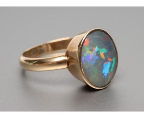 A VICTORIAN BLACK OPAL RING, the oval polished panel in a close back setting to a plain 15ct gold shank, size M 1/2 (Est. plu