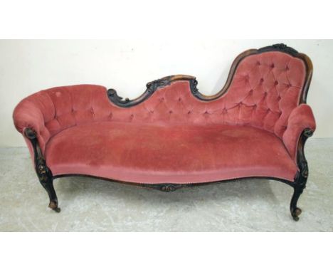 A VICTORIAN WALNUT FRAMED SOFA of serpentine outline carved with flowers and foliate scrolls and button upholstered in pink d