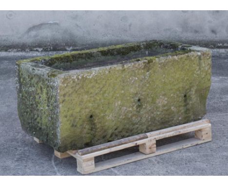 A LARGE SANDSTONE WATER TROUGH of textured oblong form, the mildly tapering sides with broad flat rim, 56" x 30 1/2" x 22" (E