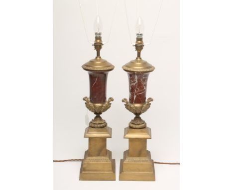 A PAIR OF BRASS AND ROUGE MARBLE TABLE LAMPS, of urn form cast with foliage and raised on a stepped square plinth, 22" to top