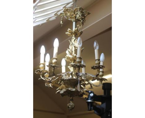 A ROCOCO STYLE BRASS EIGHT LIGHT CHANDELIER, 20th century, the central stem encased with foliate scrolls and with foliate pen