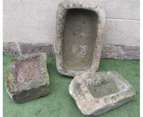 A SANDSTONE GARDEN TROUGH of rounded oblong form, rough hewn, 28 1/2" x 18 1/2" x 7 1/2", together with two similar smaller t