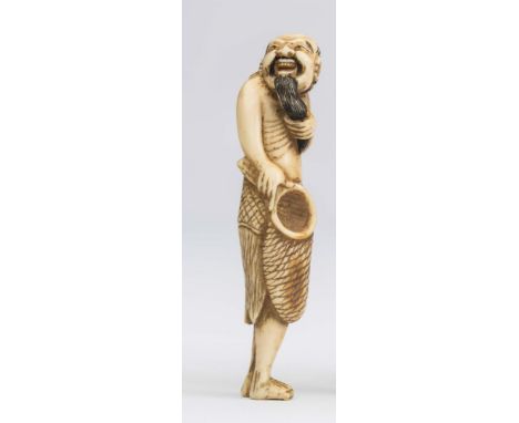 A JAPANESE IVORY NETSUKE, 18th century, carved as a fisherman, standing and holding a net in his right hand, stroking his lon