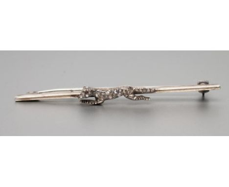 A HUNTING BROOCH, the white metal bar centred by a running fox set with numerous rose cut diamonds and a ruby eye, 2 1/4" lon