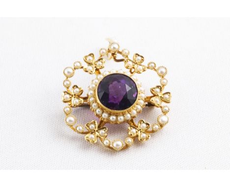 A yellow metal cluster pendant principally set with a round faceted cut amethyst measuring approximately 10.0mm and finished 