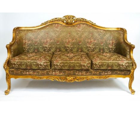 A carved giltwood and gesso Louis XV style three seater  framed sofa, the shell and foliate scroll back of rococo form, with 