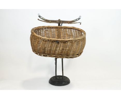 A vintage bicycle display stand, the assembled bicycle parts, including handle bars, supporting a basket, on a domed metal fo
