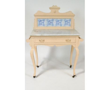 An Edwardian painted washstand with raised tiled back above a marble top, with frieze drawer, on cabriole legs with ceramic c