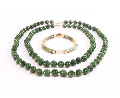 Two strands of nephrite jade beads, strung knotted and finished with gold plated clasps; A curved cylinder nephrite jade brac