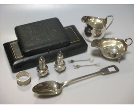 A collection of silverware including a Georgian cream jug, a Georgian basting spoon, a sauce boat, a napkin ring, a pair of p