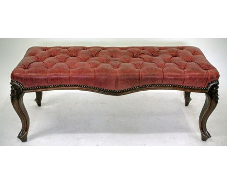 A CARVED WALNUT LONG STOOL with a maroon leather button upholstered top and cabriole legs, 118cm wide 