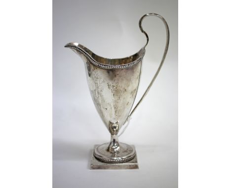 A GEORGE III SILVER HELMET SHAPED CREAM JUG, with beaded border and shaped strap handle on square pedestal base by John Lambe