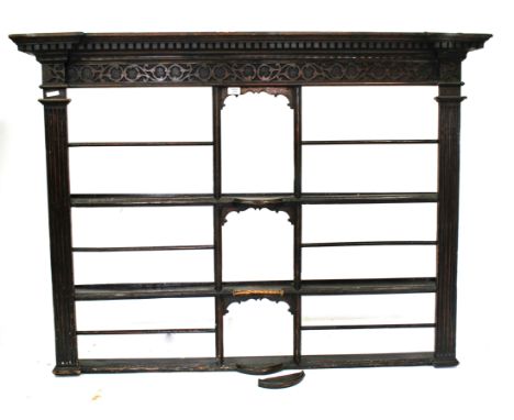 AN OAK AND STAINED PINE OPEN WALL SHELF with detail and blind fret carved cornice above three shaped open shelves with reeded