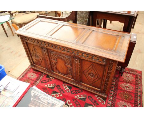 AN 18TH CENTURY STYLE OAK COFFER with a carved triple panel front 122cm wide 