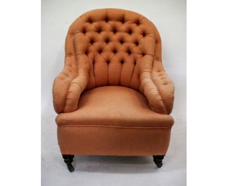 A VICTORIAN ORANGE DEEP BUTTON UPHOLSTERED ARMCHAIR with turned feet and brass and ceramic castors 77cm wide 