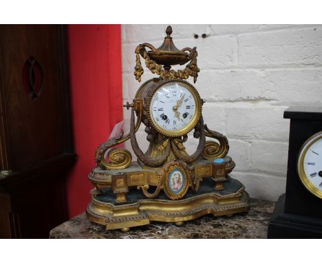 A 19TH CENTURY FRENCH GILT METAL MANTLE CLOCK, the case with floral swag mounted urn finial over a drum movement with further