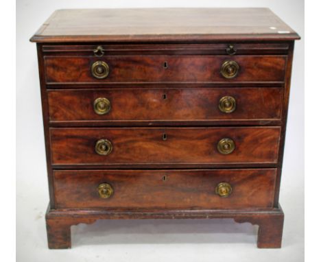 A GEORGE III MAHOGANY CHEST of four long graduated drawers with a brushing slide and brass ring handles standing on bracket f