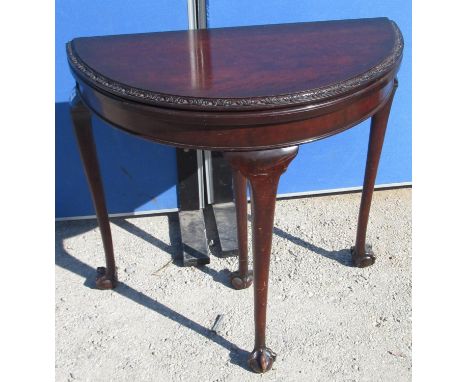Geo. III style mahogany demi lune card table, folding top with floral carved border, pull out slender cabriole legs with claw