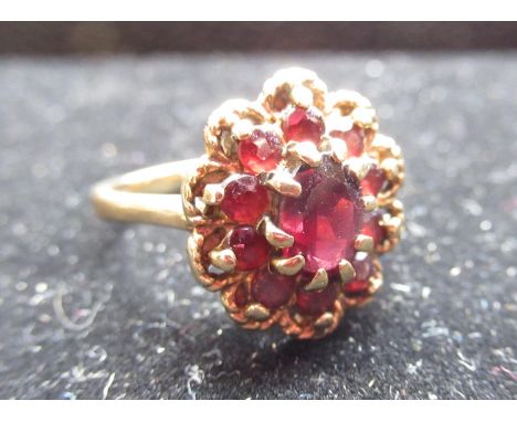Hallmarked 9ct yellow gold garnet daisy cluster ring with a central round cut, claw set garnet and a halo of ten smaller roun