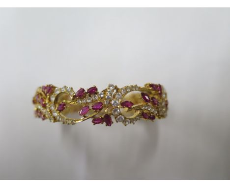 A yellow gold ruby and white stone hinged bangle, tests to approx 18ct, approx 40.9 grams, missing four white stones, but in 