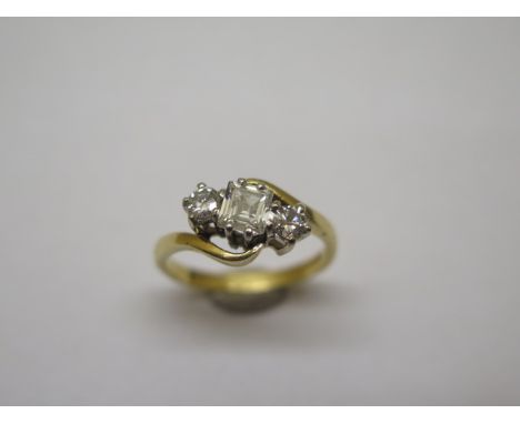 A hallmarked 18ct yellow gold three stone ring, size L, the central emerald cut diamond approx 4mm x 5mm x 2mm, in good condi