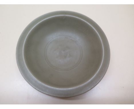 A Chinese 15th / 16th century celadon dish decorated in an even jade glaze colour with a central design of two swimming carp 