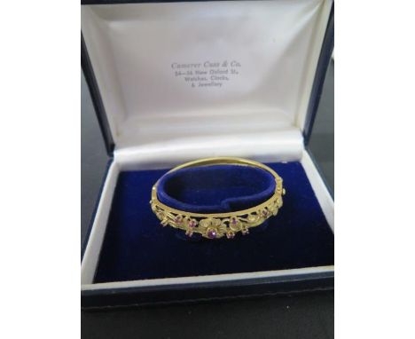 A hallmarked 9ct yellow gold ruby bangle, 5.5cm x 6cm external, approx 15 grams, missing safety chain but generally good 