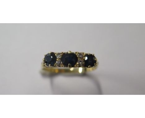 A gold sapphire and diamond seven stone carved hoop ring, with 1 4mm x 3mm oval and 2 3mm round dark blue sapphires inset wit