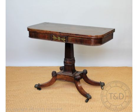 A Regency brass inlaid rosewood card table, with fold over swivel top, on a carved square column, platform and four out-swept