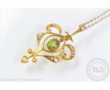An Edwardian peridot and seed pearl set pendant, of typical sinuous form with central peridot drop and set throughout with gr