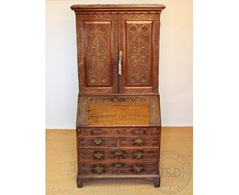 A late George III oak bureau bookcase with later carved detailing, possibly Welsh, with two panelled doors enclosing shelves,