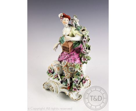An 18th century Derby porcelain figure of a shepherdess, modelled with bird cage and lamb, on a scroll base, 22.5cm, (at faul