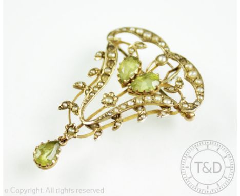 An Edwardian peridot and split seed pearl set brooch/pendant, of typical sinuous form, designed as a seed pearl surround cent