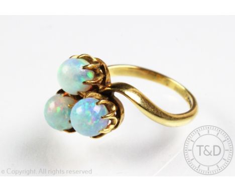 A three stone untested opal ring, each circular opal claw set in trefoil shape, within scroll shoulders and plain hoop stampe