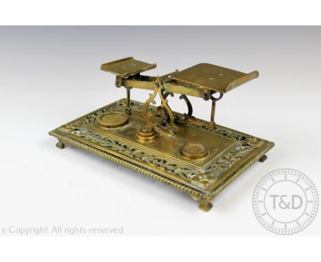 A pair of late Victorian brass postage weighing scales, on a pierced platform upon four bracket feet, with associated weights