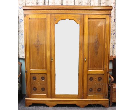 An Edwardian Arts and Crafts inlaid walnut wardrobe, with three doors, two doors carved with sun flowers, on bracket feet, 21