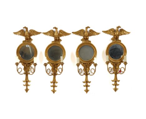 A SET OF FOUR REGENCY STYLE GILT WOOD CIRCULAR WALL MIRRORS (4)With eagle crest over twin branch light sconces, 26cm diameter