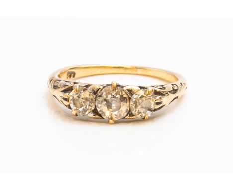 A GOLD AND DIAMOND THREE STONE RINGClaw set with a row of cushion shaped diamonds, the mount decorated with scrolled sides, d