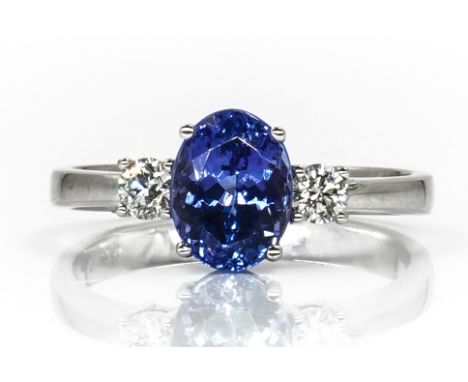 A WHITE GOLD, TANZANITE AND DIAMOND THREE STONE RINGClaw set with the oval cut tanzanite between two circular cut diamonds, d